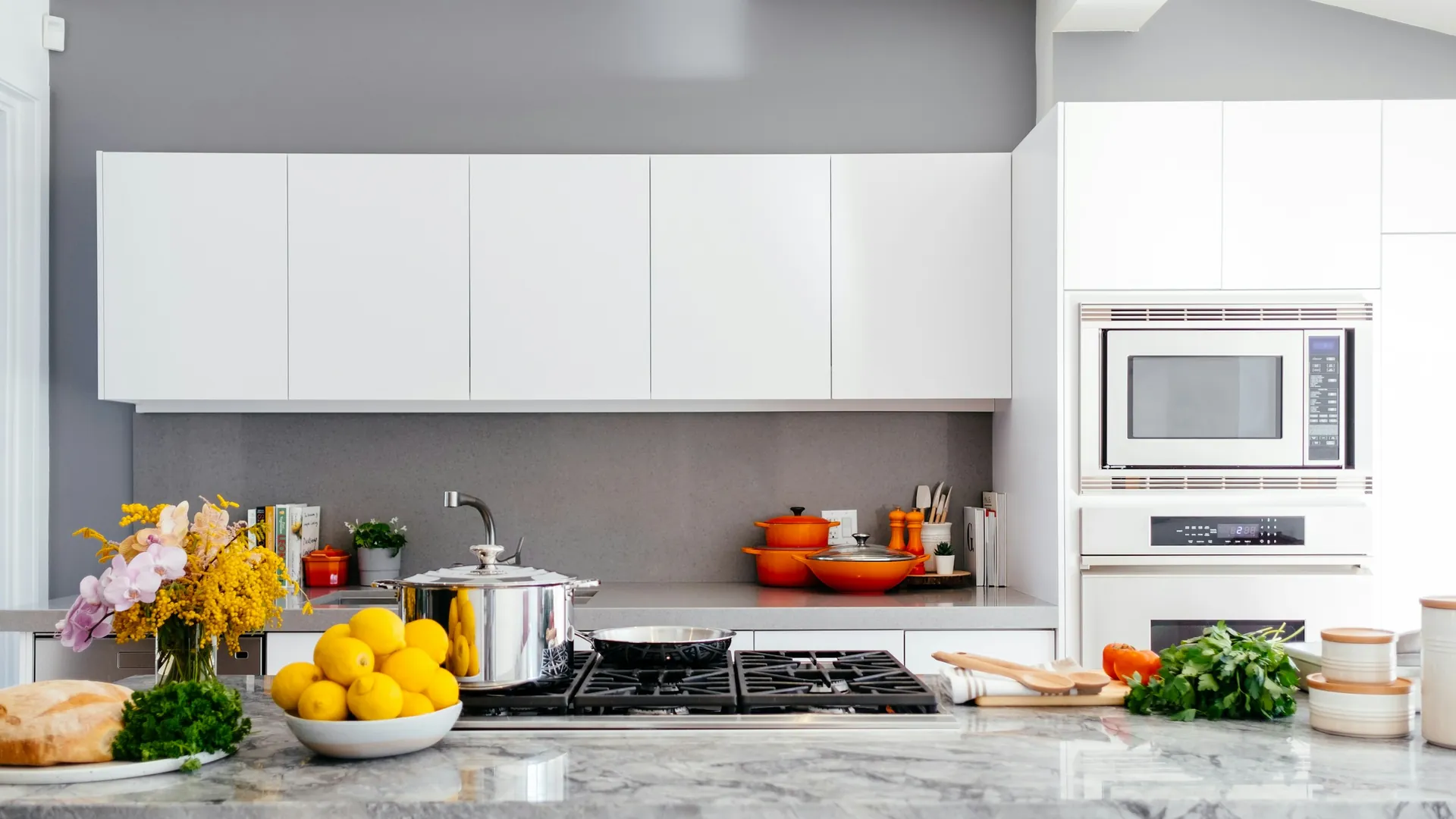 White kitchen with gray backsplash, orange cookware